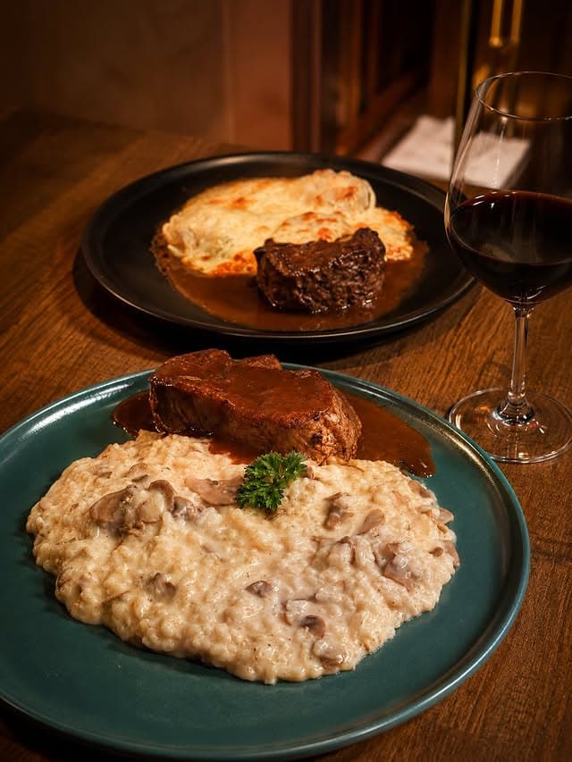 Filé ao molho poivre sobre risoto cremoso de funghi, acompanhado de taça de vinho tinto